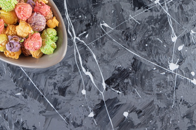 Gray bowl of delicious colorful popcorns on marble table. 