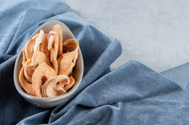 Gray bowl of healthy dried apple rings on stone background.