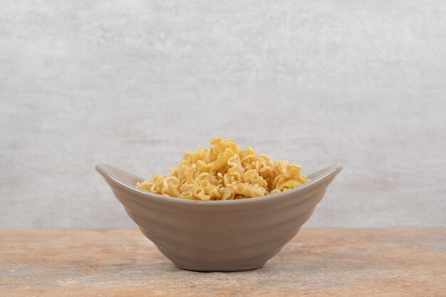 A gray bowl of unprepared macaroni on marble background. High quality photo