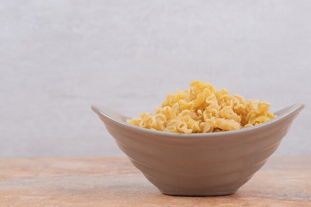 A gray bowl of unprepared macaroni on marble background. High quality photo
