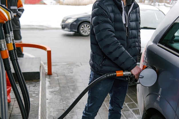 The gray car is refueling at the gas station the man inserted a gasoline hose into the gas tank Premium Photo