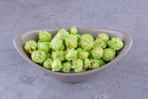 Free photo gray oval bowl with flavorous candy coated popcorn on marble background. high quality photo