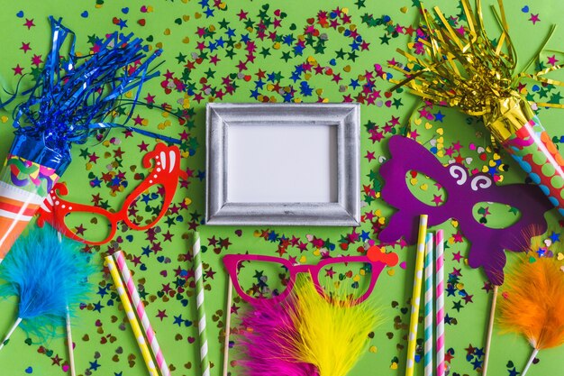 Gray photo frame with confetti, colorful glasses and sticks seen from above