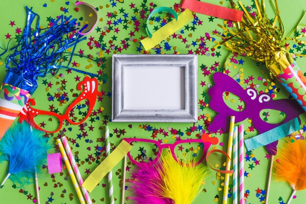 Gray photo frame with confetti, colorful glasses and sticks seen from above
