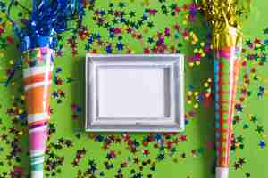 Free photo gray photo frame with confetti and colorful trumpets