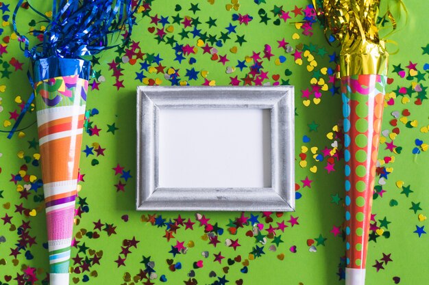 Gray photo frame with confetti and colorful trumpets