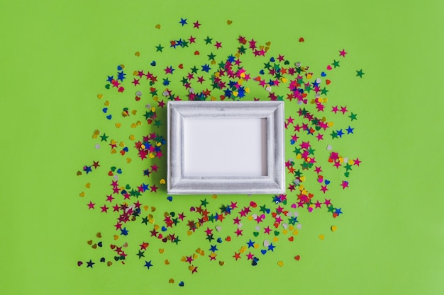 Free photo gray photo frame with confetti on a green background