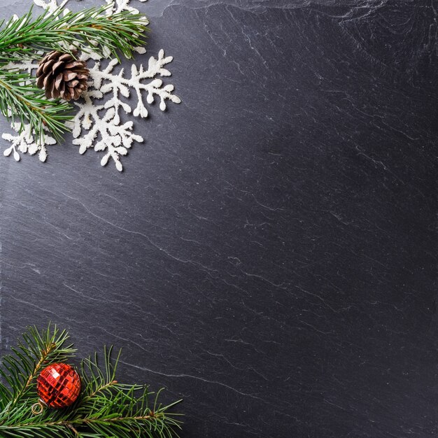 クリスマスの装飾用の松の枝とコピースペースのある雪の結晶のある灰色の表面