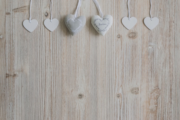 Free photo gray and white hearts hanging on ropes on a wooden surface