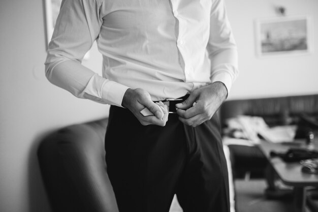 Grayscale closeup of a businessman tightening his belt and getting ready for an important meeting