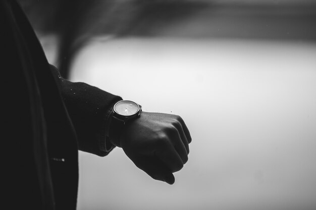 Grayscale closeup shot of a person wearing a wristwatch