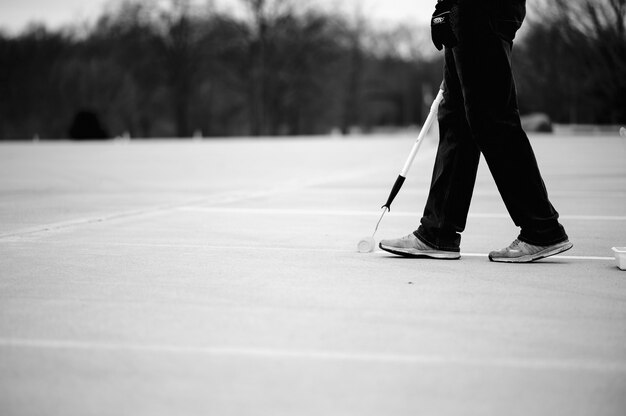 Grayscale of a man painting lines on a parking lot