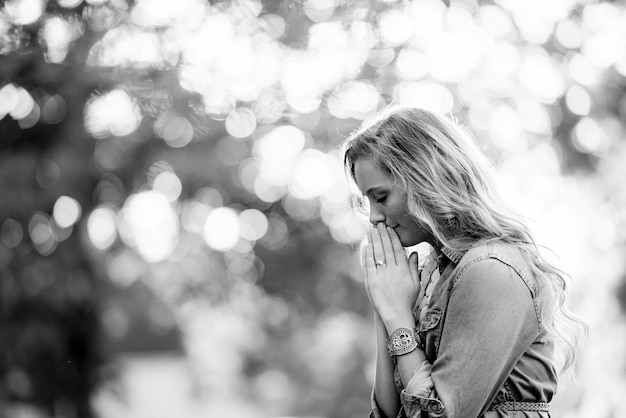 Grayscale, selective shot of a blonde female praying