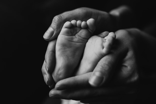 grayscale shot of the baby feet in mother hands