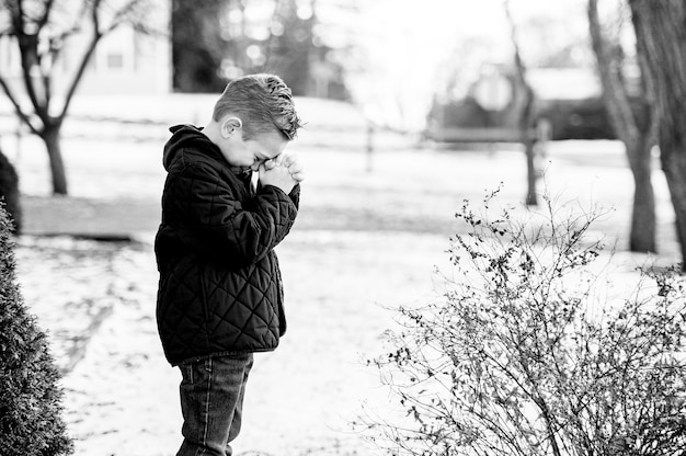 Снимок молящегося ребенка в оттенках серого