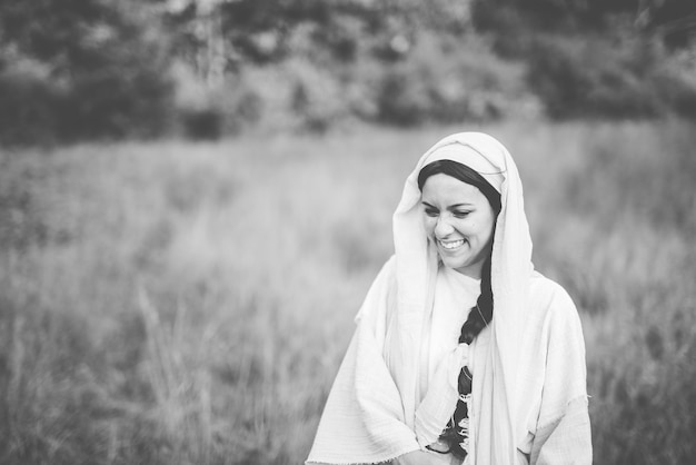 Grayscale shot of a female wearing a biblical robe and laughing