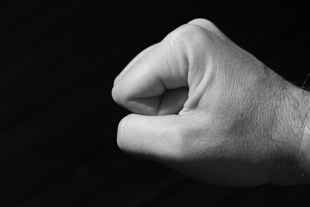 Полутоновый снимок кулака человека на черном фоне