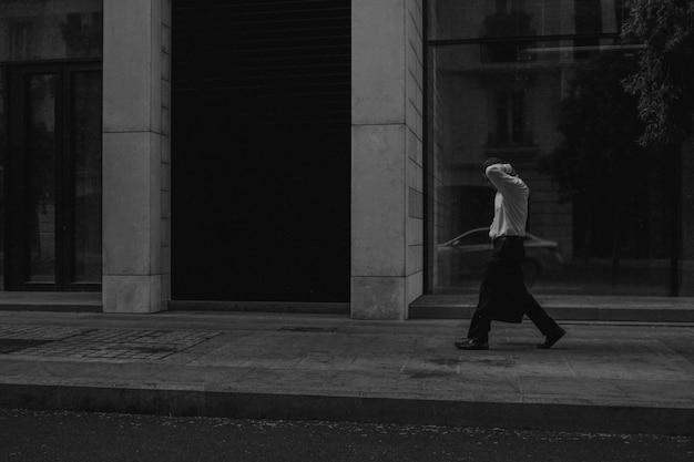 Free photo grayscale shot of a male walking along a pedestrian zone near a building
