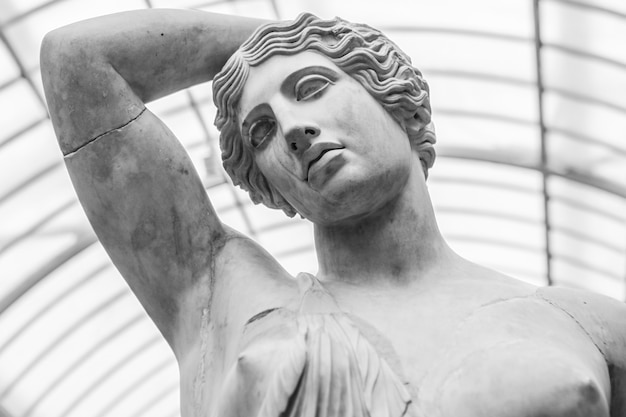 Grayscale shot of a marble statue of a female under the lights