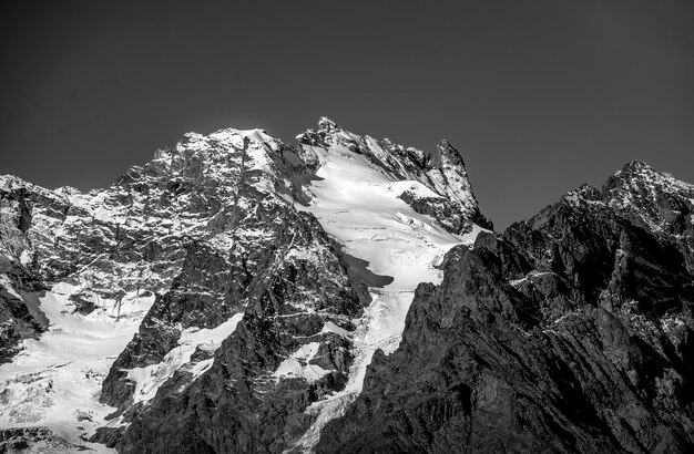 Grayscale shot of mountains with parts of it covered in snow