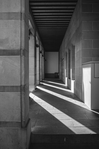 Grayscale shot of an outer corridor with shadows of beams