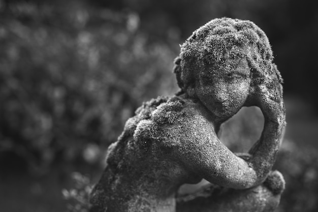 Grayscale shot of stone sculptures in a garden