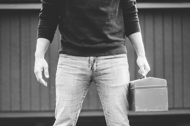 Grayscale shot of a technician holding a toolbox