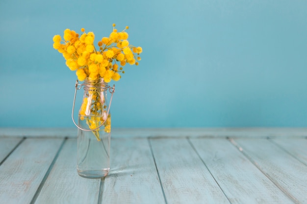 Great background with wooden surface, vase and yellow flowers