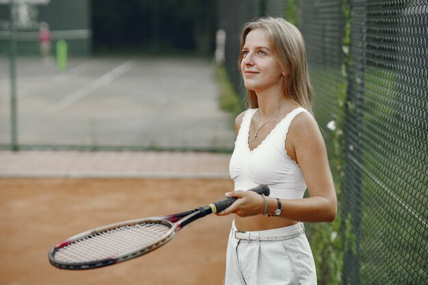 プレーするのに素晴らしい日です！ Tシャツを着た元気な若い女性。テニスラケットとボールを保持している女性。