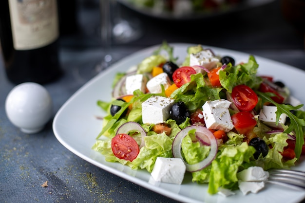 Греческий салат нарезанные оливки красное вино внутри белой тарелке