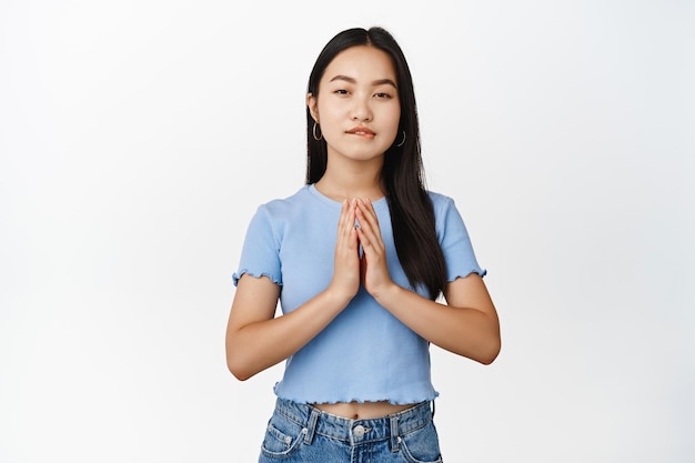 Greedy asian girl scheming steeple fingers and squinting coy having evil genius plan standing thoughtful over white background