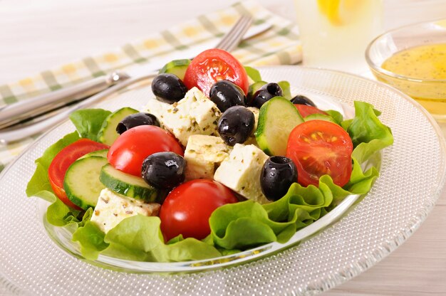 Greek salad in glass bowl with sauce