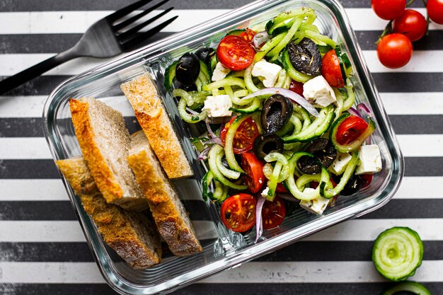 Greek salad with bread in a glass container