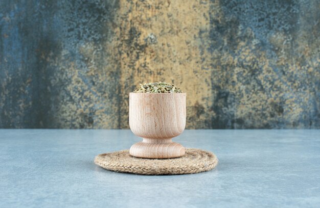 Зеленые семена аниса в деревянной чашке на синем фоне. Фото высокого качества