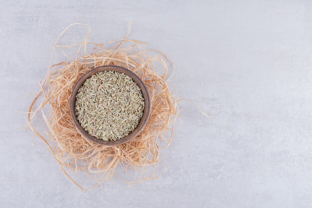 Green anise seeds in a wooden cup on concrete surface