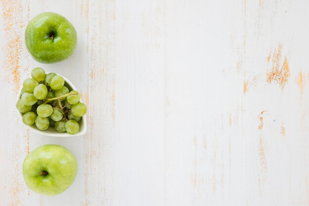 Green apple and grapes on white wooden background