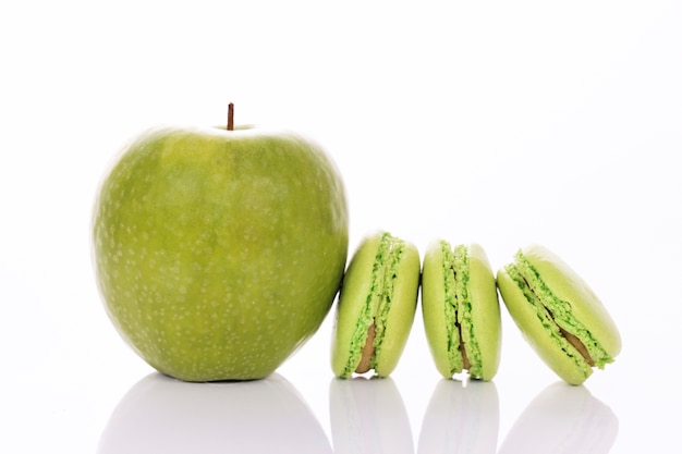 Green apple with macaroons on white background