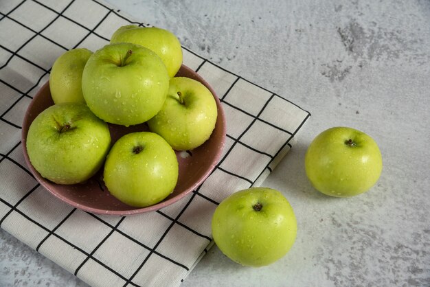 Green apples in a ceramic saucer on the table