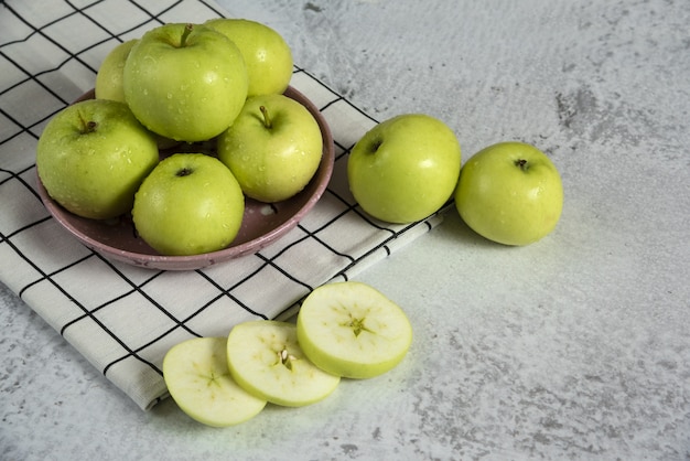Green apples in a ceramic saucer on the towel, top view
