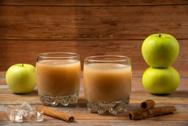 Green apples, cinnamon sticks and two cups of fresh juice on the table