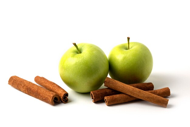 Green apples and cinnamons isolated on white