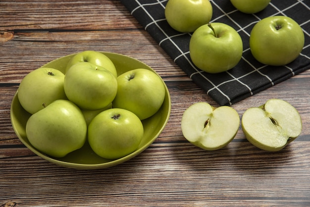 Green apples in a green ceramic bowl on a checked towel