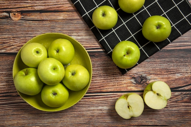 Green apples in a green ceramic bowl on a checked towel