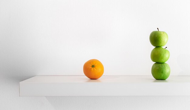 Green apples and orange on a white background closeup