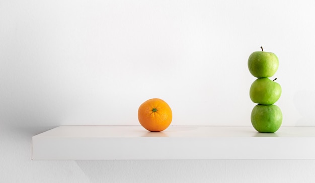 Зеленые яблоки и апельсин на белом фоне крупным планом