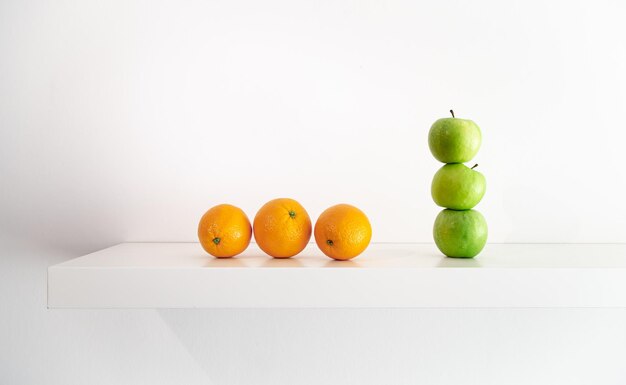 Green apples and oranges on a white background closeup