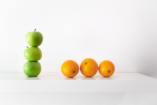 Green apples and oranges on a white background closeup