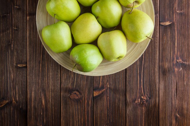 나무 배경에 접시에 녹색 사과. 평면도. 텍스트를위한 공간