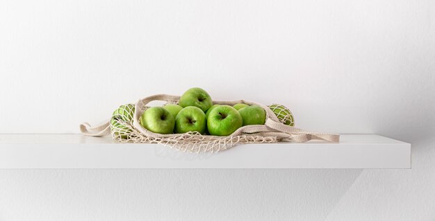 Green apples in a string bag on a white background