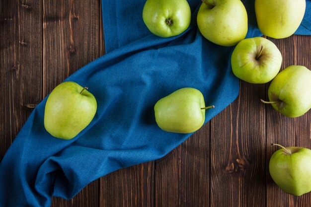 青い布と木製の背景に緑のリンゴのトップビュー